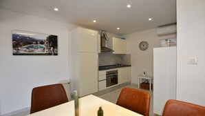Cocina pequeña con fregadero, estufa y un reloj en la pared.