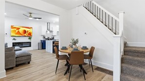 Ein modernes Wohnzimmer mit Essbereich, einer Treppe und einer Küche im Hintergrund.