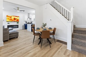 A modern living room with a dining area, a staircase, and a kitchen in the background. - Newly Renovated 4 BR near downtown Indy w Garage! (Indianapolis)