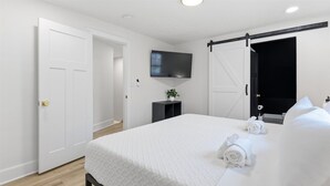 Ein Hotelzimmer mit einem Bett, einem Fernseher, einer Tür und einem kleinen Tisch mit einer Pflanze.