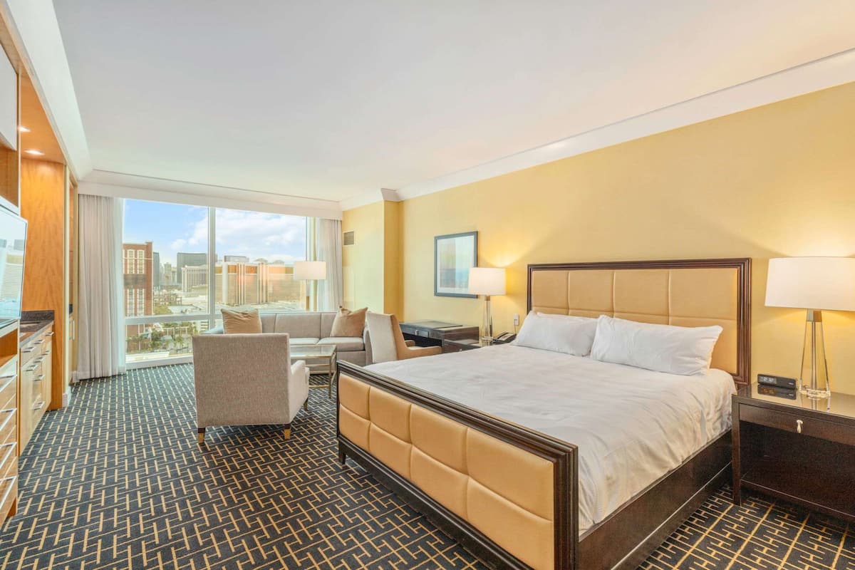 Une chambre d’hôtel avec un grand lit, un canapé, un bureau et une vue sur la ville.