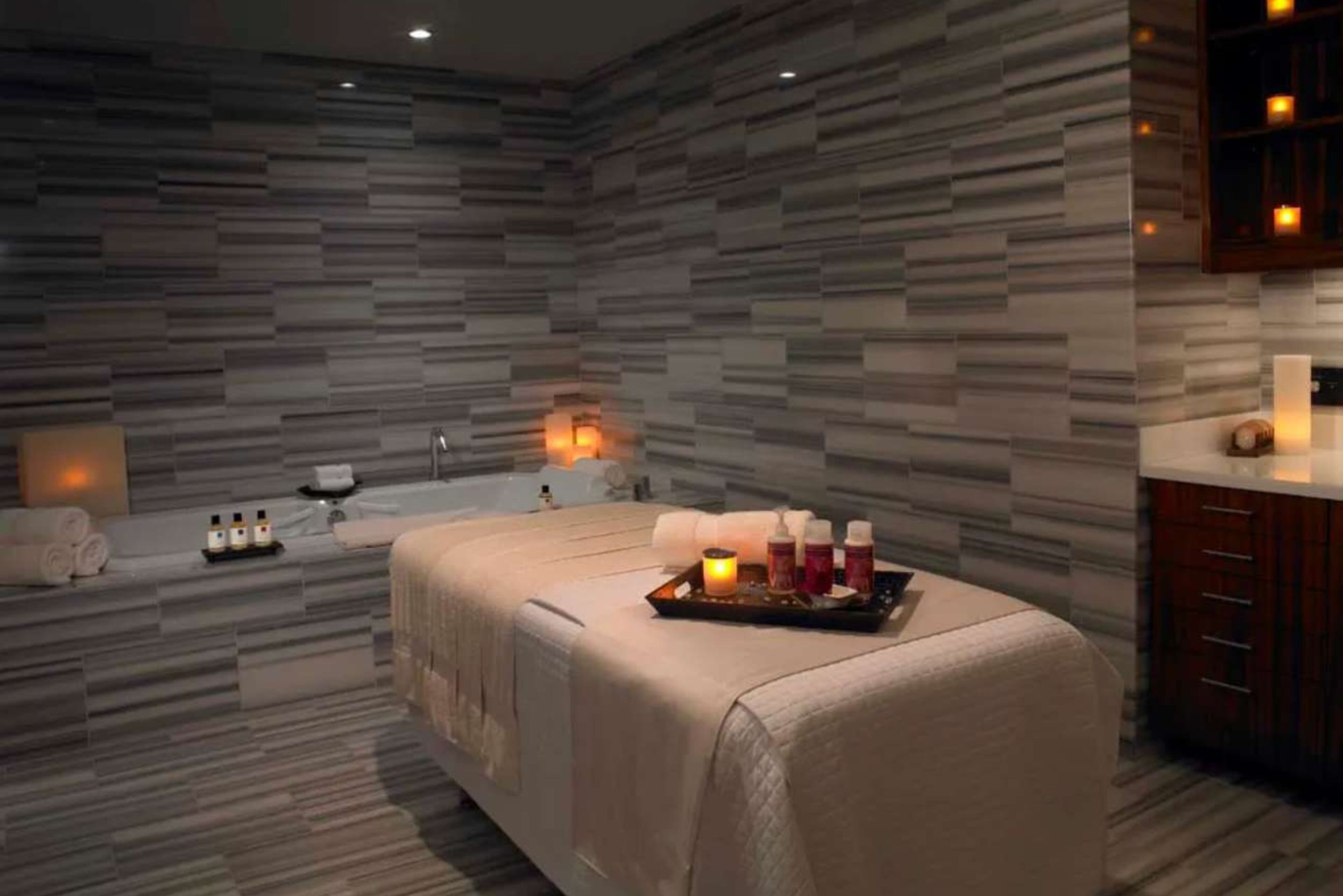 A spa room with a massage table, candles, and toiletries.