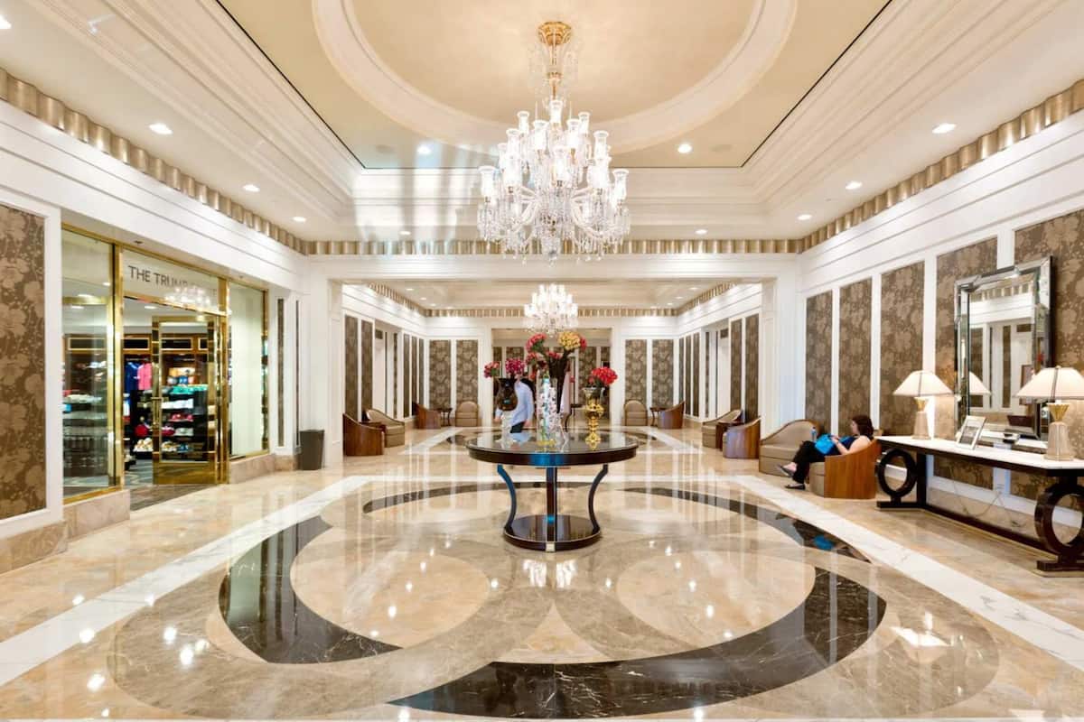 Un hall d’entrée spacieux, doté d’une table ronde centrale, de lustres et d’un magasin appelé « THE TRUMP ».