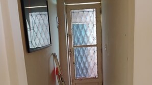 A hallway with a door, a ladder, and a striped rug.
