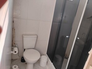 Un baño pequeño con inodoro, bidé y cabina de ducha de vidrio.