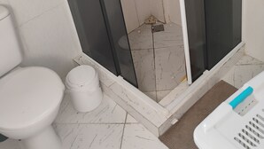 A bathroom with a toilet, a shower with a glass door, and a sink.