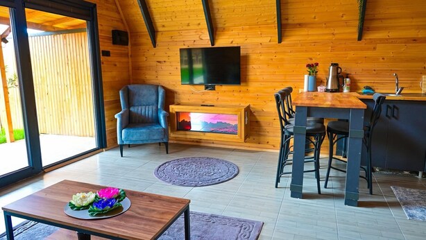 Ein gemütliches Zimmer mit Kamin, Fernseher, Essbereich und großem Fenster.