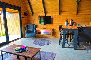 A cozy room with a fireplace, a television, a dining area, and a large window. - La Maison Bungalov (Ondokuzmayis)