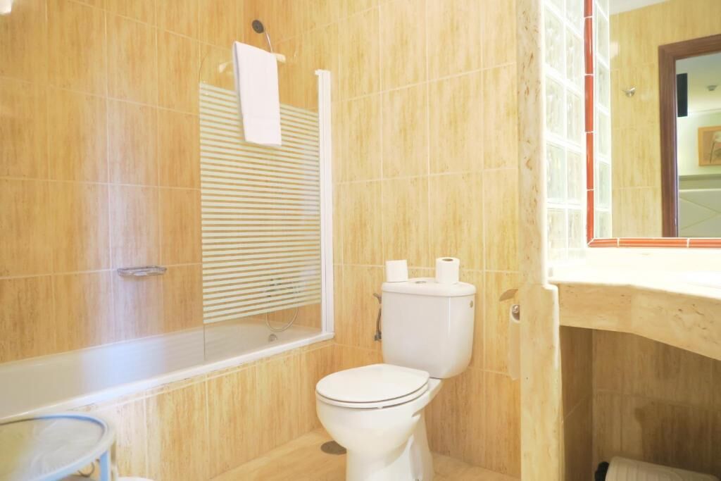 Une salle de bain comprenant des toilettes, un espace douche et un miroir.