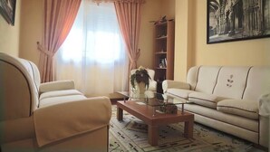A living room with a sofa, armchair, coffee table, and a bookshelf. - My Rooms Hotel Camiño do Mar (Rois)