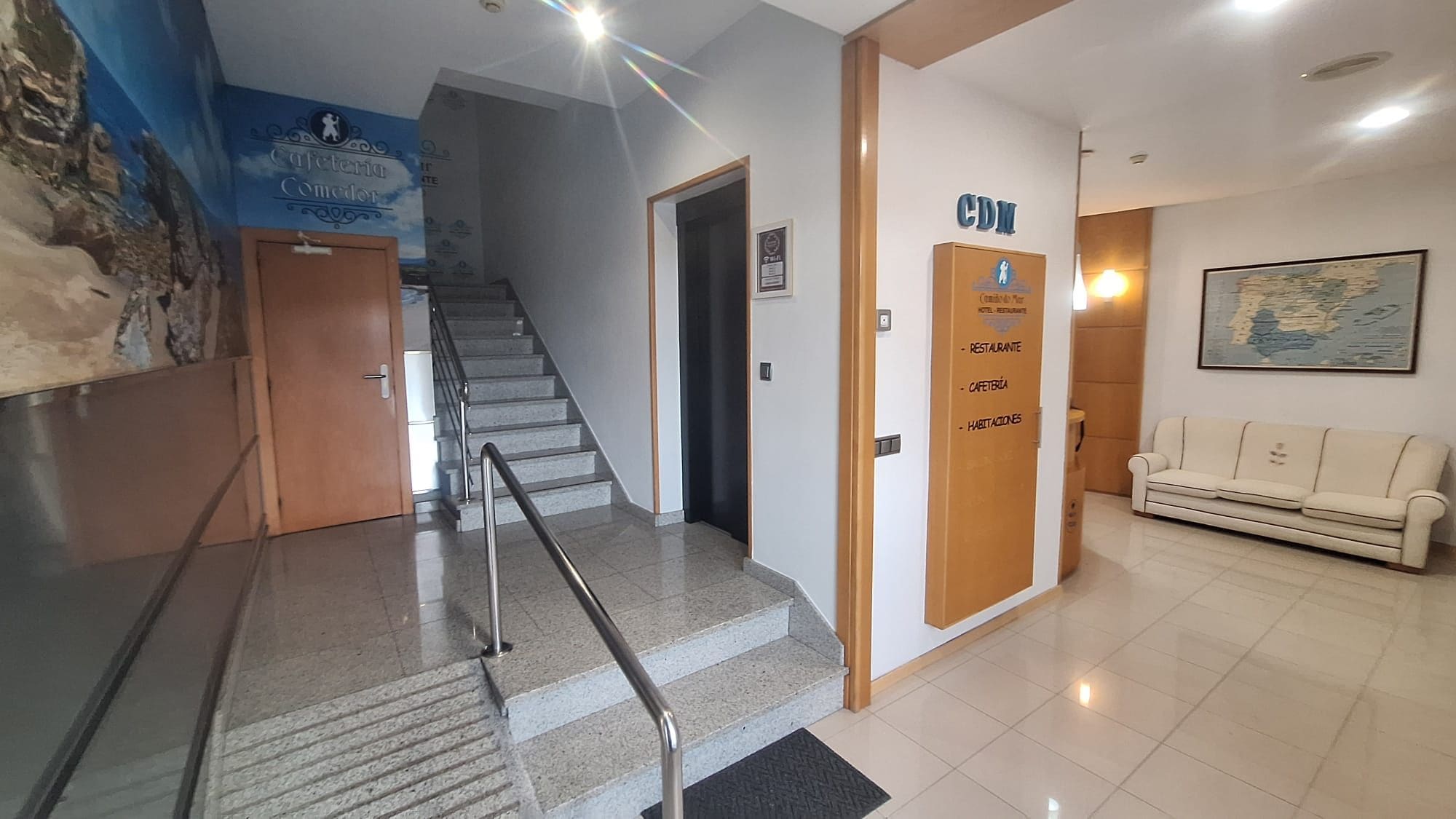 A hotel lobby with a staircase, a reception desk, and a sofa.