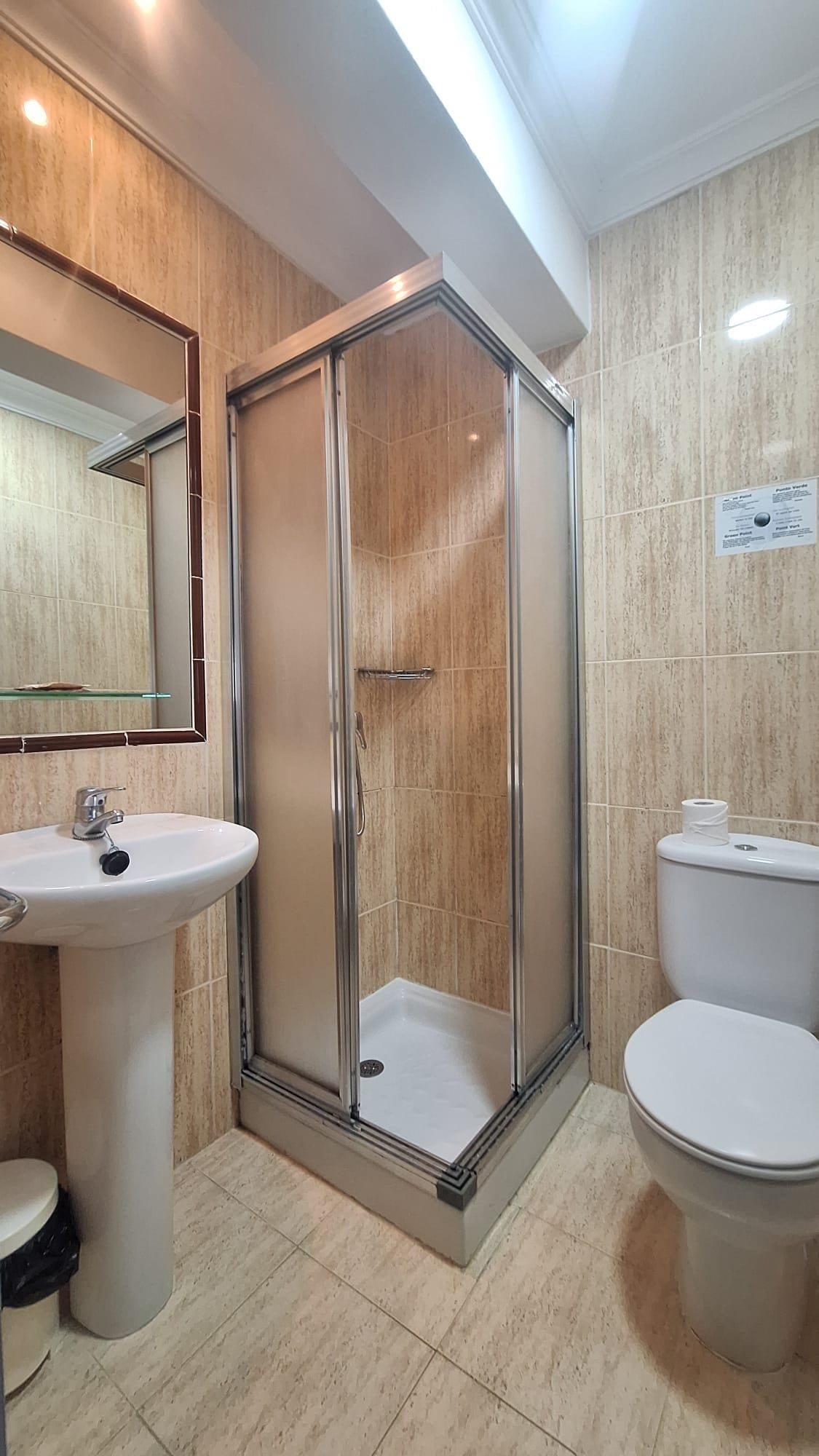 Un baño con ducha de vidrio, lavamanos e inodoro.