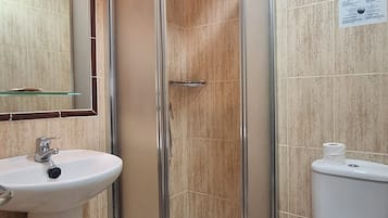 Un baño con ducha de vidrio, lavamanos e inodoro.