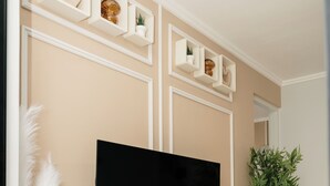 Een flatscreen televisie bevestigd aan een houten tv-meubel, met decoratieve planken erboven.