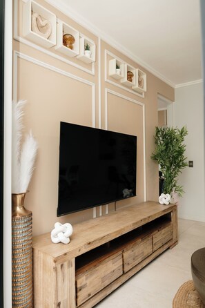 Ein Flachbildfernseher an einem HolztV-Möbel mit dekorativen Regalen darüber.