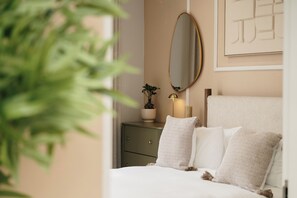 Ein Schlafzimmer mit einem Bett, einem Schminktisch, einem Spiegel und einer Zimmerpflanze.