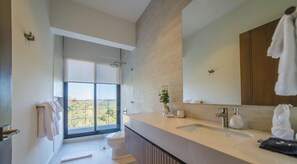 Un baño moderno con un ventanal grande, lavamanos doble y un espejo amplio.