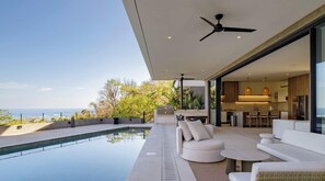 Un espacio exterior moderno con piscina, zona de estar y vista al océano.