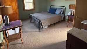 A bedroom with a bed, a desk, a chair, a window, and a door.