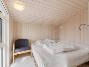 A room with a bed, a chair, and a wall-mounted lamp. - 4 Star Holiday Home in Lokken (Lokken)