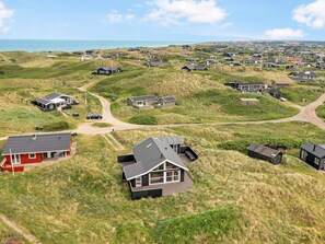 A coastal residential area with houses on dunes, a clear sky, and a view of the sea. - 4 Star Holiday Home in Lokken (Lokken)