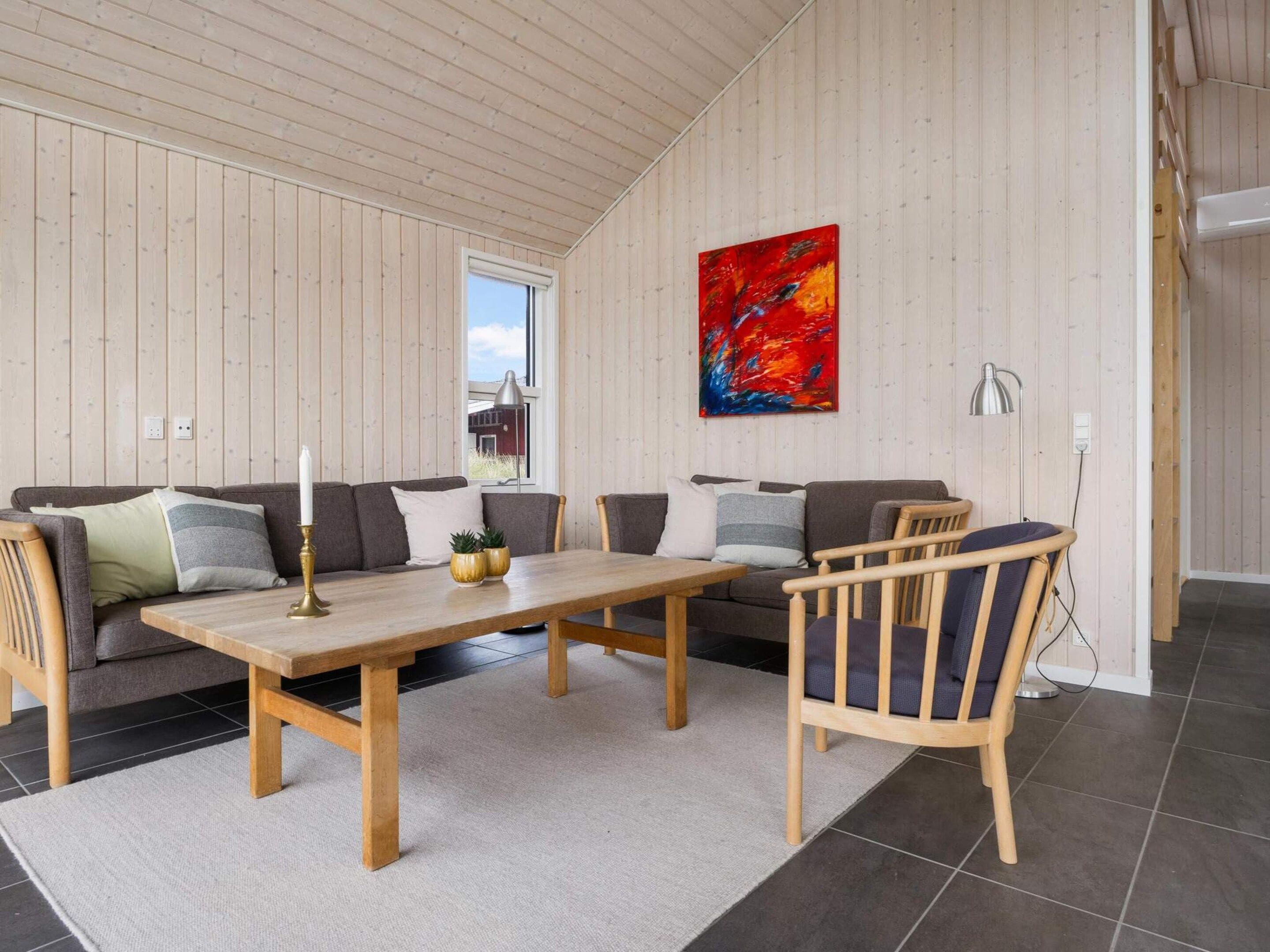 A modern living room with a wooden ceiling, a large abstract painting, a sofa set, a dining table, and a chair.