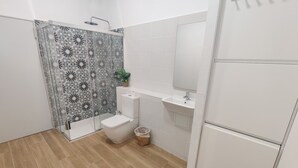 Ein Badezimmer mit Dusche, Toilette, Waschbecken und Spiegel.
