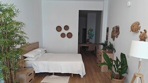 Ein Schlafzimmer mit Bett, Nachttischen, Schreibtisch, Stuhl und einer Topfpflanze.