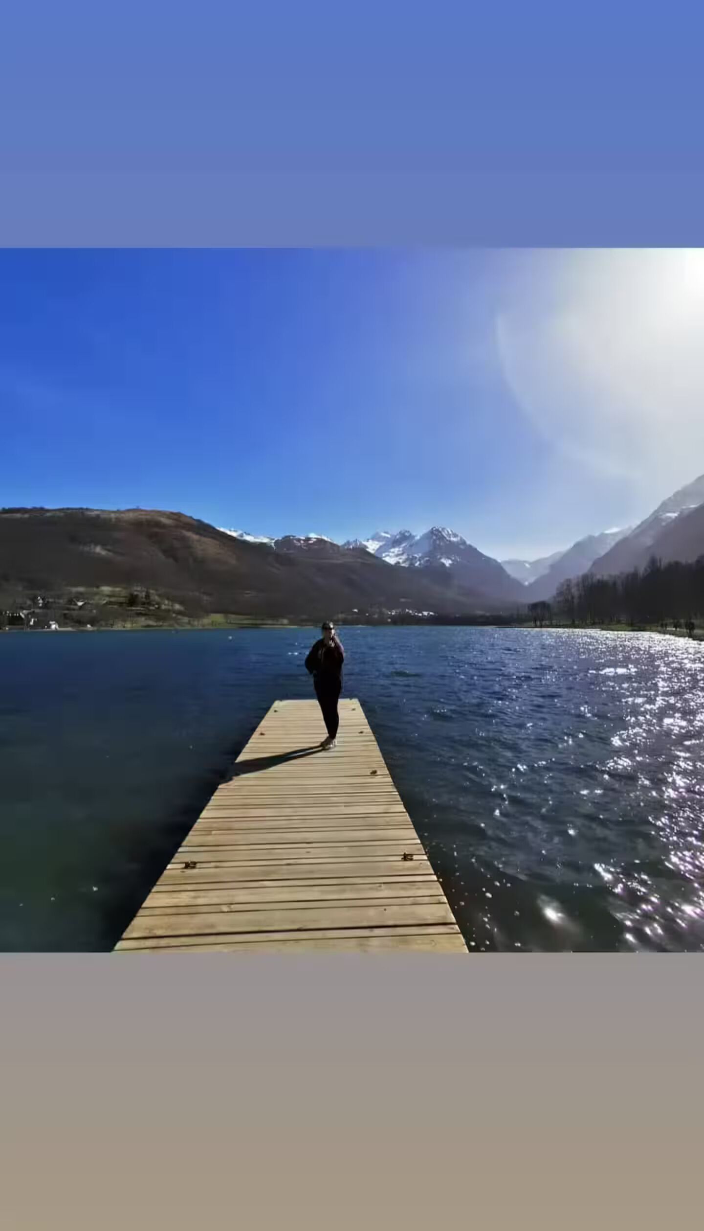 Un muelle de madera que se adentra en un lago, con montañas al fondo.