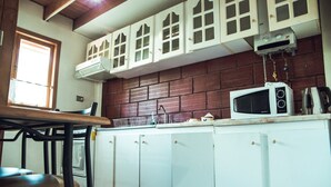 A kitchen with white cabinets, a microwave, and a window. - Apartamento en la Patagonia Chilena (Puerto Aysen)