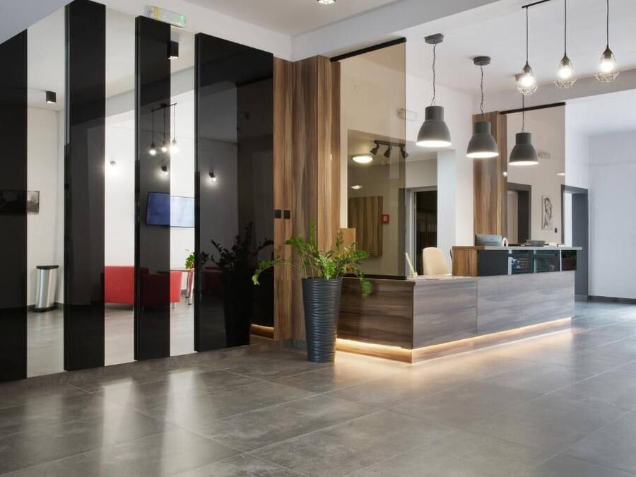 A modern reception area with a counter, potted plants, and pendant lighting.