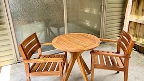 A round wooden table with four chairs, a sliding glass door, and a wooden fence. - Oaks Cottages Modern 2BR Retreat (Lafayette)