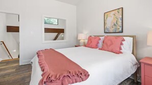A bedroom with a bed, bedside tables, a window, and a painting on the wall. - Oaks Cottages Modern 2BR Retreat (Lafayette)