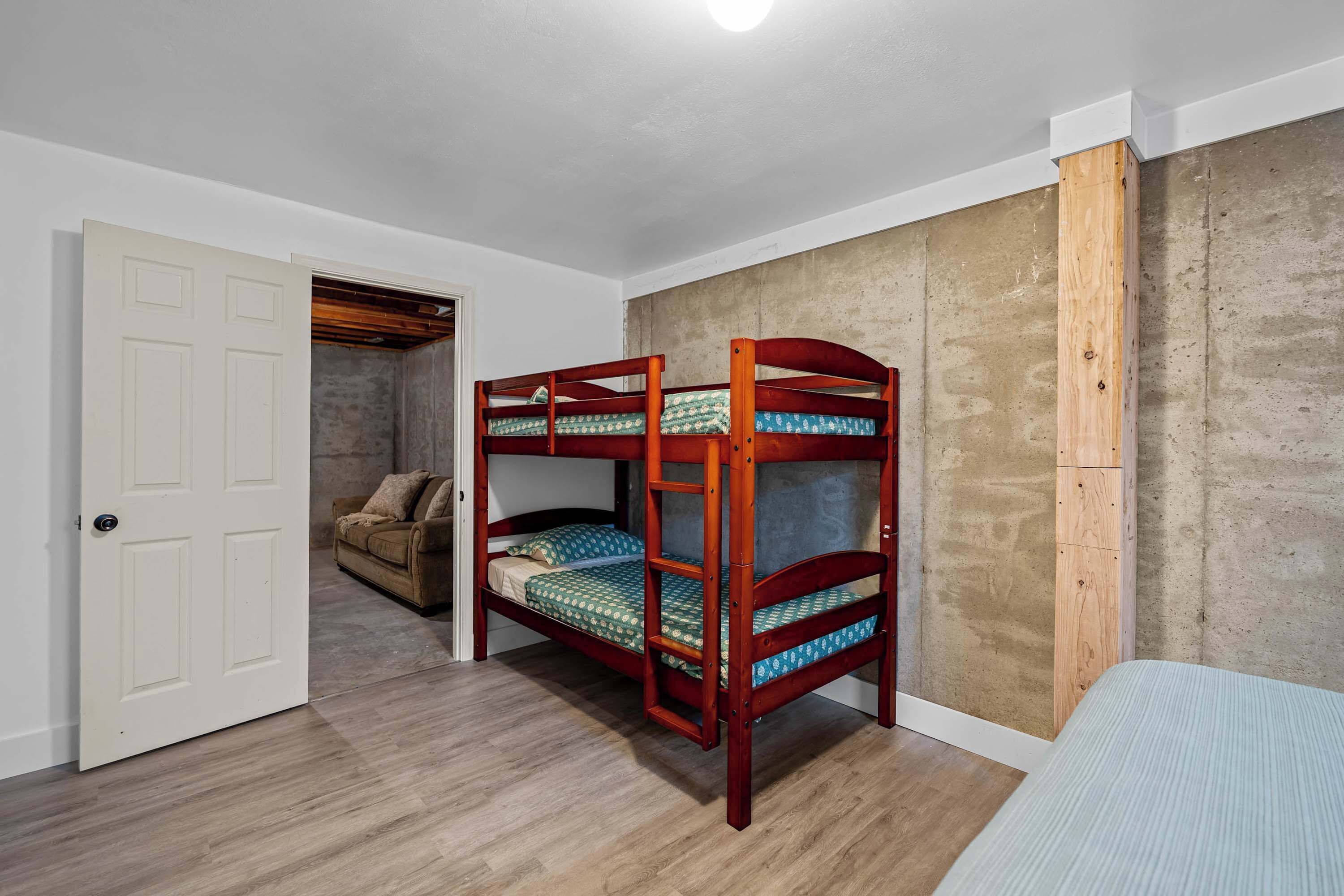 Un lit superposé avec une structure en bois, une porte blanche et un mur en béton.