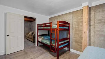 Un lit superposé avec une structure en bois, une porte blanche et un mur en béton.