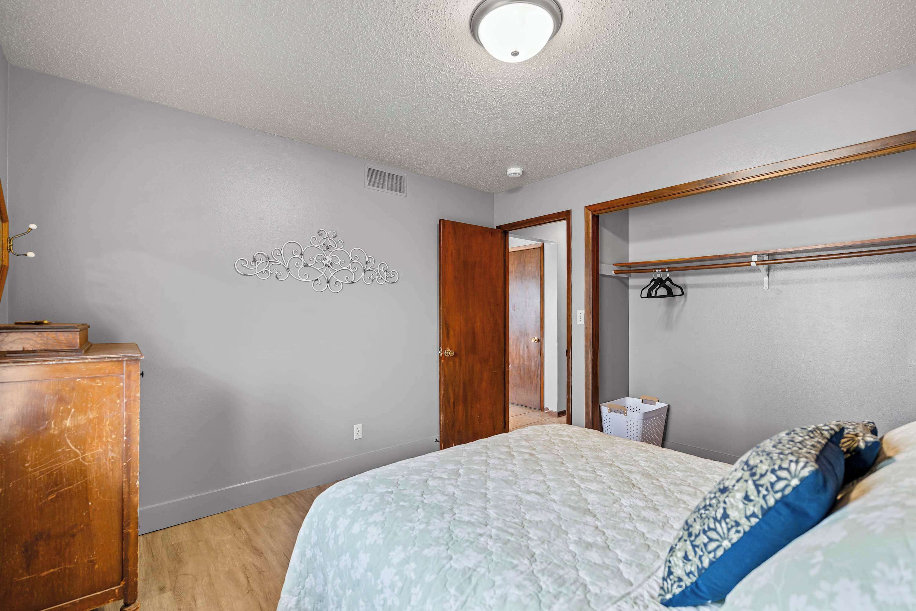 A bedroom with a bed, wooden dresser, and a mirror.