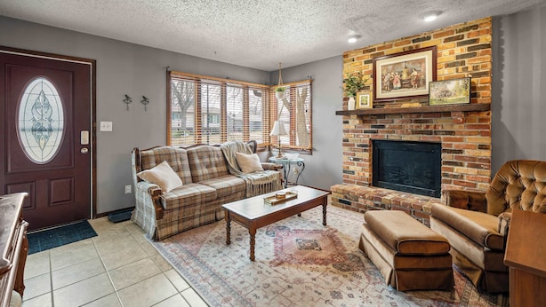 A living room with a fireplace, a sofa set, a coffee table, and a door with a stained glass design. - 3BR-2BA, Sleeps 8 | Close to I-35 (Ames)