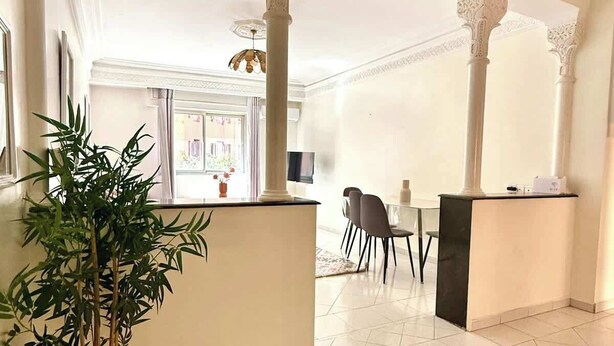 A spacious room with a tiled floor, a reception desk, and a large potted plant. - 2-bedroom apartment for 6 in Gueliz near the train station (Marrakesh)