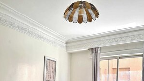 A living room with a beige sofa, a patterned rug, a wooden coffee table, and a decorative ceiling light. - 2-bedroom apartment for 6 in Gueliz near the train station (Marrakesh)