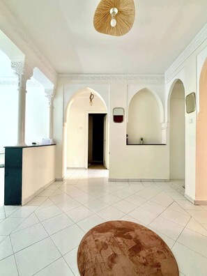 Eine großzügige Lobby mit einer Rezeption, einem großen braunen Hocker und einem Deckenventilator.