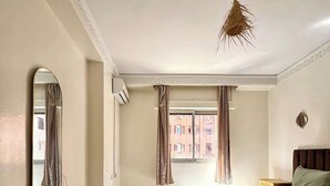 A bedroom with a bed, a rug, a mirror, and a window with curtains. - 2-bedroom apartment for 6 in Gueliz near the train station (Marrakesh)