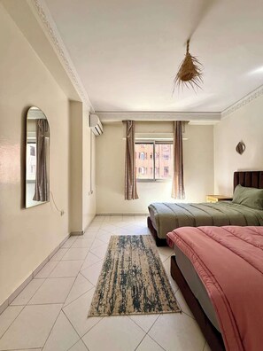 Ein Schlafzimmer mit Bett, Teppich, Spiegel und einem Fenster mit Vorhängen.