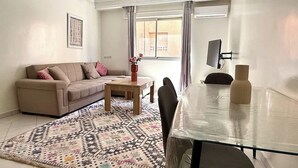 A living room with a sofa, coffee table, and dining table. - 2-bedroom apartment for 6 in Gueliz near the train station (Marrakesh)