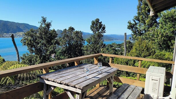 Eine Holzterrasse mit Tisch und Stühlen mit Blick auf einen See und Berge.