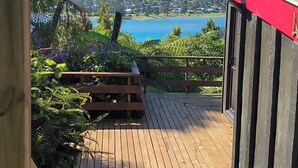 Eine Holzterrasse, die zu einer Aussichtsplattform mit Blick auf das Meer und die Hügel führt.
