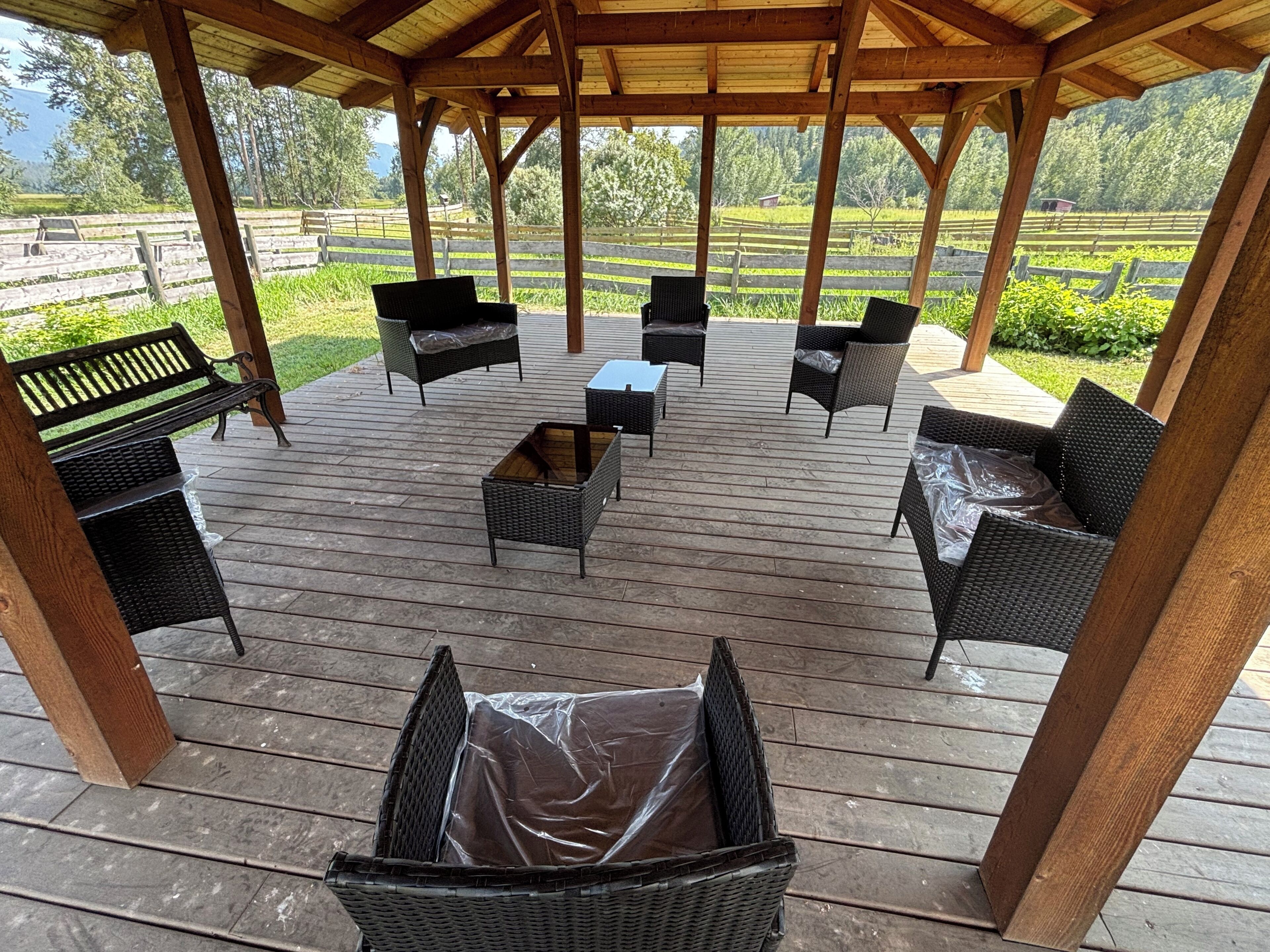An outdoor wooden deck with wicker furniture and a pergola structure.