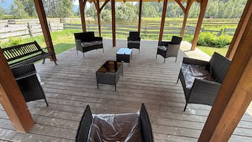 An outdoor wooden deck with wicker furniture and a pergola structure.