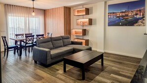 Un salon moderne comprenant un canapé d’angle, une table à manger avec des chaises, une table basse et des étagères encastrées en bois.