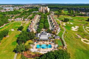 An aerial view of a resort with a central pool, multiple buildings, and golf courses. - EPIC Seven Eagles Escape (Kissimmee)