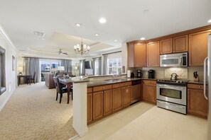 A modern kitchen with wooden cabinets, stainless steel appliances, and a large island. - New! Sunset Luxe Retreat at Reunion (Kissimmee)